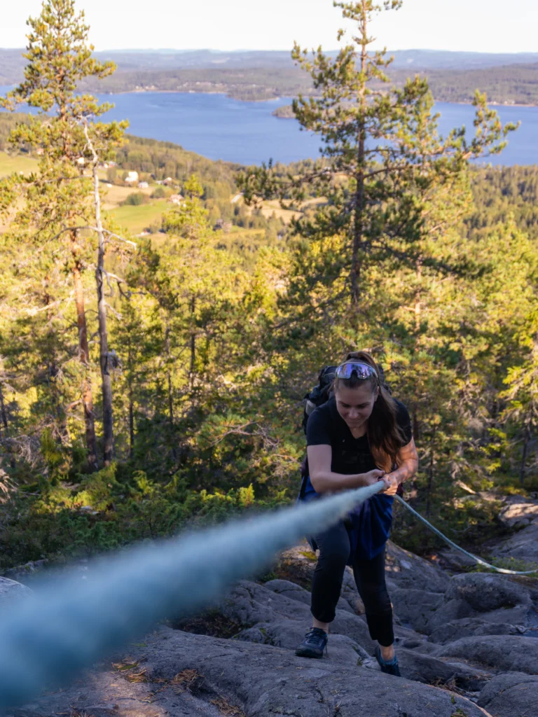 Randonneuse escaladant une paroi rocheuse avec corde, aventure en Haute Côte, Suède